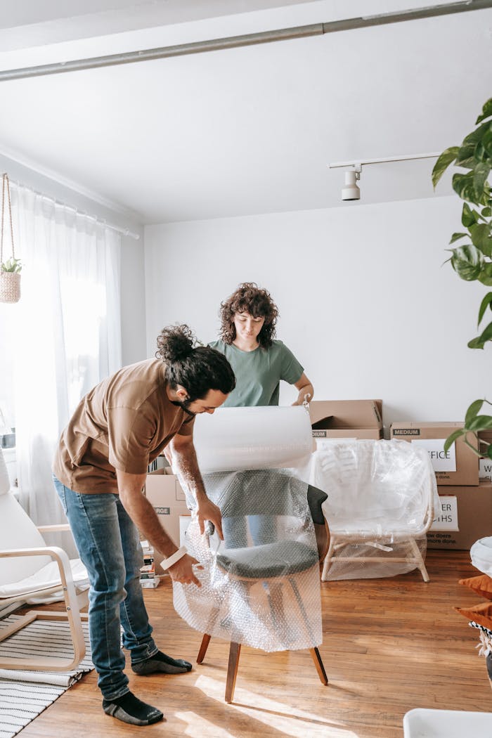 services-04 A couple busy wrapping a chair for their move. Bright and organized indoor setting.